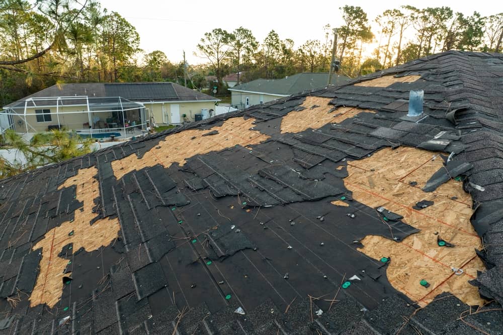 Storm damaged roof with missing shingles and exposed roof foundation